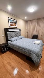 a bedroom with a large bed with a blue blanket at Apartamento VIP LEO in Tacna