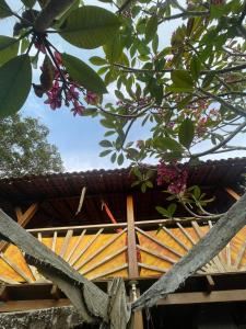 a wooden building with a roof and some flowers at Vila Entreluas in Morro de São Paulo