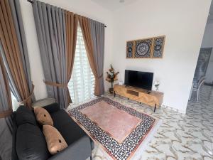a living room with a couch and a television at Villa Camellia in Langgar