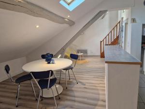 Una habitación con una mesa y sillas y una escalera. en Le grand logis de Meung Sur Loire, en Meung-sur-Loire