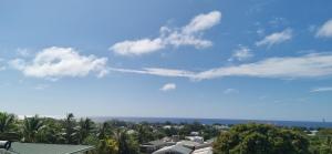 a blue sky with clouds and trees and buildings at Ocean Beach Town View - Infinity Pool in Avarua +1 photo
