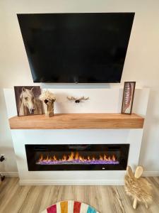 ein Fernseher über einem Kamin mit einem Fernseher darüber in der Unterkunft Brand New Cabin with Fire Pit & Outdoor Projector in Duck Creek Village