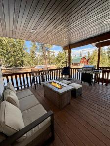 eine Terrasse mit einem Sofa und einer Feuerstelle auf einer Terrasse in der Unterkunft Brand New Cabin with Fire Pit & Outdoor Projector in Duck Creek Village