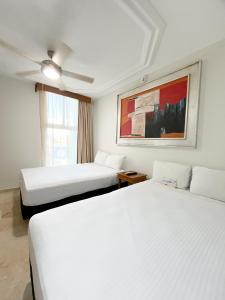 a hotel room with two beds and a ceiling fan at Quality Inn Mazatlan in Mazatlán