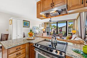 a kitchen with a stove top oven next to a living room at Mahina Surf 117 in Honokowai