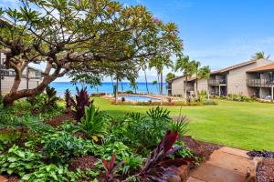 a landscaped yard with a house and the ocean at Mahina Surf 117 in Kapalua