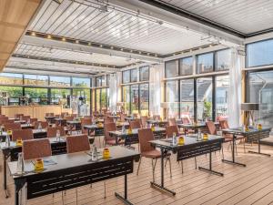 a restaurant with tables and chairs and windows at Pullman Budapest in Budapest