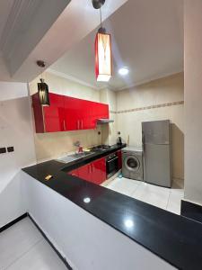 cocina con armarios rojos y encimera negra en Beachfront bliss, en Tánger