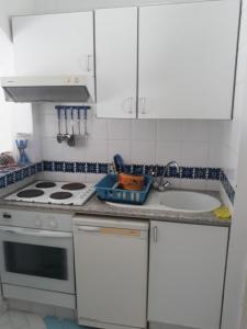 a kitchen with white cabinets and a stove and a sink at Tulip in Sousse