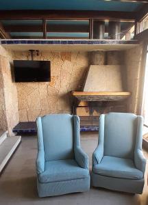 two blue chairs sitting in a room with a tv at Tongoy Bauhaus - Alojamiento hasta 12 personas in Tongoy