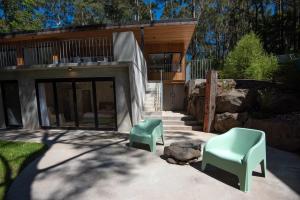 zwei grüne Stühle vor einem Gebäude in der Unterkunft Daydream Cottage Beachside Luxury in Lilli Pilli in Surf Beach