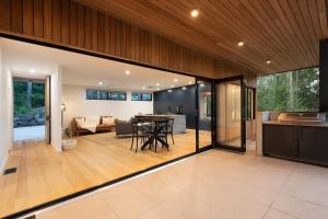 eine offene Küche und ein Wohnzimmer mit einem Tisch in einem Haus in der Unterkunft Daydream Cottage Beachside Luxury in Lilli Pilli in Surf Beach