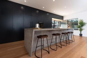 eine Küche mit einer Betontheke und Hockern in der Unterkunft Daydream Cottage Beachside Luxury in Lilli Pilli in Surf Beach + 23 Fotos