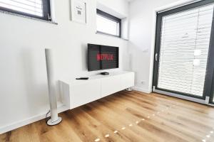 a living room with a tv on a white cabinet at Green Alpine Nest in Komenda