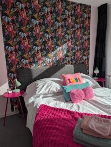 a bedroom with a bed with pink and purple pillows at Pink Hotel B&B LeLa in Valkenburg