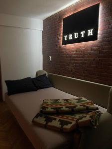 a bed in a room with a sign on a brick wall at TRUTH Apartment Veles in Veles +3 photos