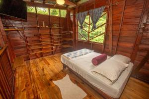 Un dormitorio con una cama en una habitación con suelo de madera. en Utopia Bluff Beach Off Grid Jungle Retreat By The Sea, en Bocas Town