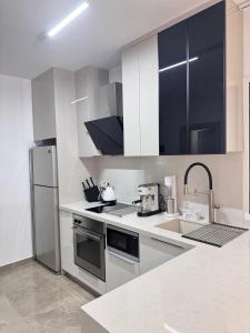 La cuisine blanche est équipée d'un évier et d'un réfrigérateur. dans l'établissement Luxury Beach Villa 2 min Walk to Sea & Airport, à Meneou