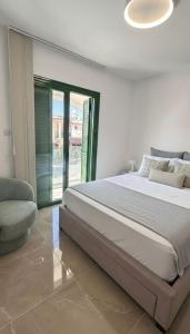 une chambre blanche avec un lit et une chaise dans l'établissement Luxury Beach Villa 2 min Walk to Sea & Airport, à Meneou