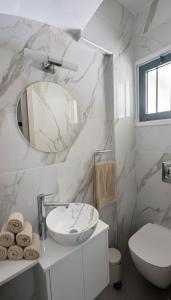 une salle de bain avec un lavabo, des toilettes et un miroir dans l'établissement Luxury Beach Villa 2 min Walk to Sea & Airport, à Meneou 7 autres photos