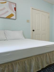 a white bed in a bedroom with a painting on the wall at Central Upscale New Kingston Apt with pool in Kingston