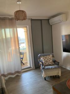 a living room with a chair and a sliding glass door at Studio belle vue in Sète