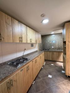an empty kitchen with wooden cabinets and a stove at Hostelfc Movistar57 in Bogotá
