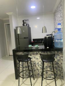 eine Küche mit einer Theke mit zwei Stühlen und einem Kühlschrank in der Unterkunft Céu e mar Rua marechal Hermes da Fonseca 37 Praia Grande centro Espaço todo reservado para hóspede in Arraial do Cabo