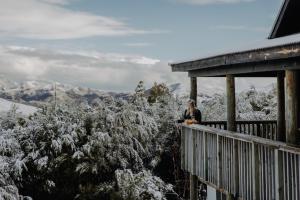 a woman standing on the balcony of a snow covered mountain at Alpine Haven, Peaceful , Stunning Views - ML21396 in Mt Lyford
