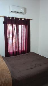 ein Schlafzimmer mit einem Bett mit einem roten Vorhang in der Unterkunft Casa en Pueblo Esther in Pueblo Esther