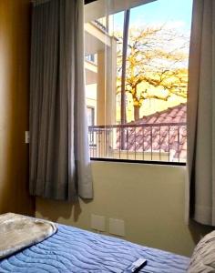 a bedroom with a bed and a large window at Vila Del Rei - Flat no Centro de São João Del rei in São João del Rei