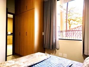 a bedroom with a bed and a window with a balcony at Vila Del Rei - Flat no Centro de São João Del rei in São João del Rei