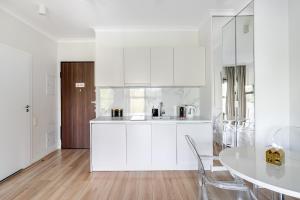 eine Küche mit weißen Schränken sowie einem weißen Tisch und Stühlen in der Unterkunft Luxury 2-room apartment with a beautiful city view in Warschau + 9 Fotos