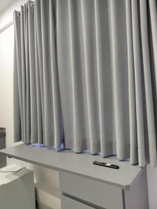 a window with white curtains on top of a desk at Vila Del Rei - Flat no Centro de São João Del rei in São João del Rei +17 photos