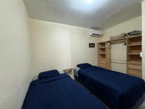 two beds in a room with blue sheets at Excelente apartamento para 4 personas in Monterrey