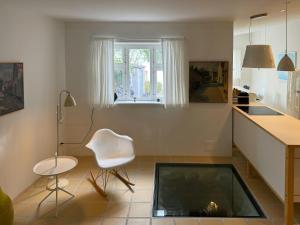 a living room with a white chair and a window at Town House With Sea View In Historic Ærøskøbing in Ærøskøbing +11 photos