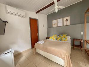 a bedroom with a bed with yellow and blue pillows at Paraiso Mar in Búzios