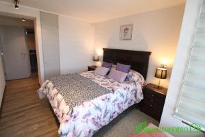 a bedroom with a large bed with purple pillows at MPH 204 Departamento en Puerto Varas a pasos del Lago, para 6 personas in Puerto Varas