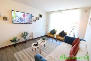 a living room with a couch and a tv on a wall at MPH 204 Departamento en Puerto Varas a pasos del Lago, para 6 personas in Puerto Varas