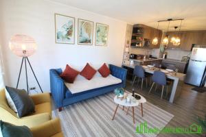 a living room with a blue couch and a kitchen at MPH 204 Departamento en Puerto Varas a pasos del Lago, para 6 personas in Puerto Varas