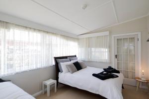 1 Schlafzimmer mit 2 Betten und weißen Vorhängen in der Unterkunft Heritage Home with BBQ & Outdoor Fire Pit in Tenterfield