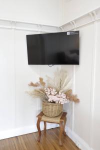 Ein Fernseher hängt an der Wand, auf einem Tisch steht ein Blumenkorb. in der Unterkunft Homely 2-Bed Cottage Near Tenterfield Centre in Tenterfield