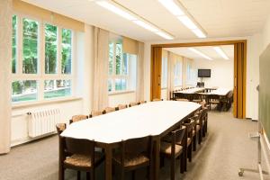 einen Konferenzraum mit Tischen, Stühlen und Fenstern in der Unterkunft Seminarhaus Europäische Akademie in Waren (Müritz)