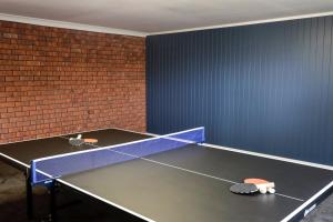 una mesa de ping pong en una habitación con una pared de ladrillo en Country 4-Bed Homestead with Games Room & Views, en Tenterfield