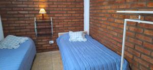 zwei Betten in einem Zimmer mit einer Ziegelwand in der Unterkunft Nuevo Complejo Milena in San Juan + 2 Fotos