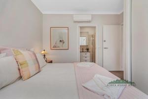 1 dormitorio con cama blanca y manta rosa en Campaspe Central - Your Central Echuca Escape!, en Echuca