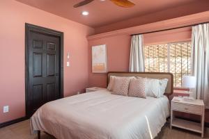 a bedroom with a bed with pink walls and a window at Rosarito Rosé in Las Gaviotas