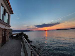a sunset over a body of water with a house at Apartment Starigrad - Senj 1 in Starigrad +17 photos