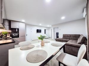 uma cozinha e sala de estar com uma mesa e cadeiras brancas em BunApart Ciorescu Cristal em Ciorescu