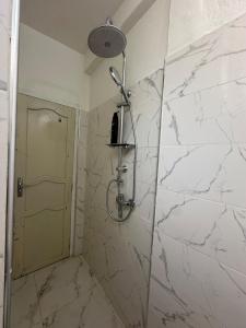 Un baño con ducha con pared de mármol blanco. en A unique and cute apartment in a prime location, en Er Rachidia